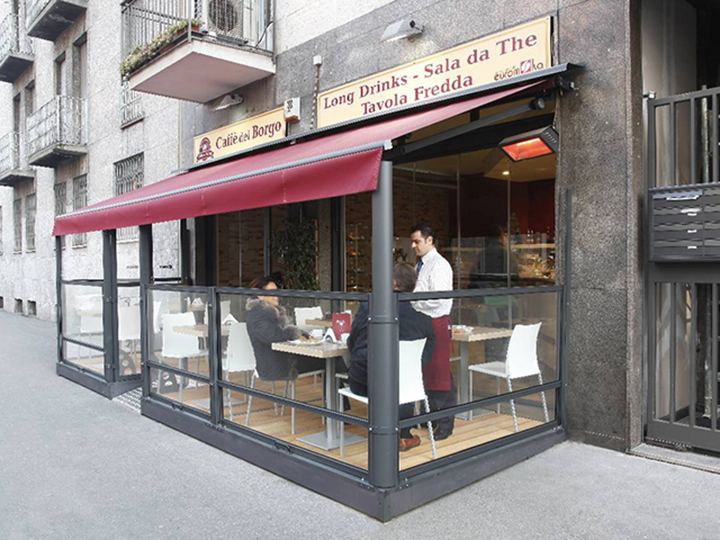 small cafe with red awning and glass dividers for outdoor seating